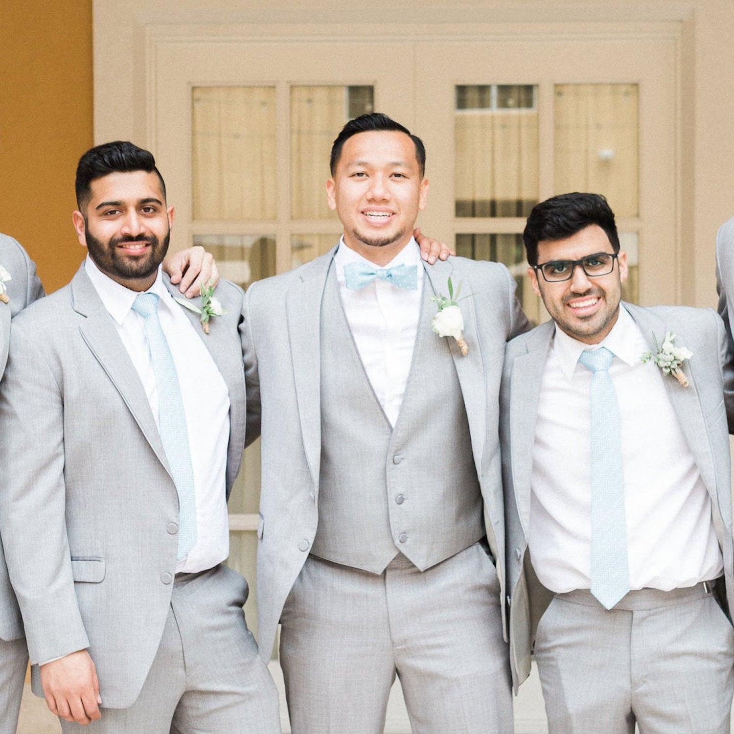 three men wearing light blue neckties and bow ties at a wedding
