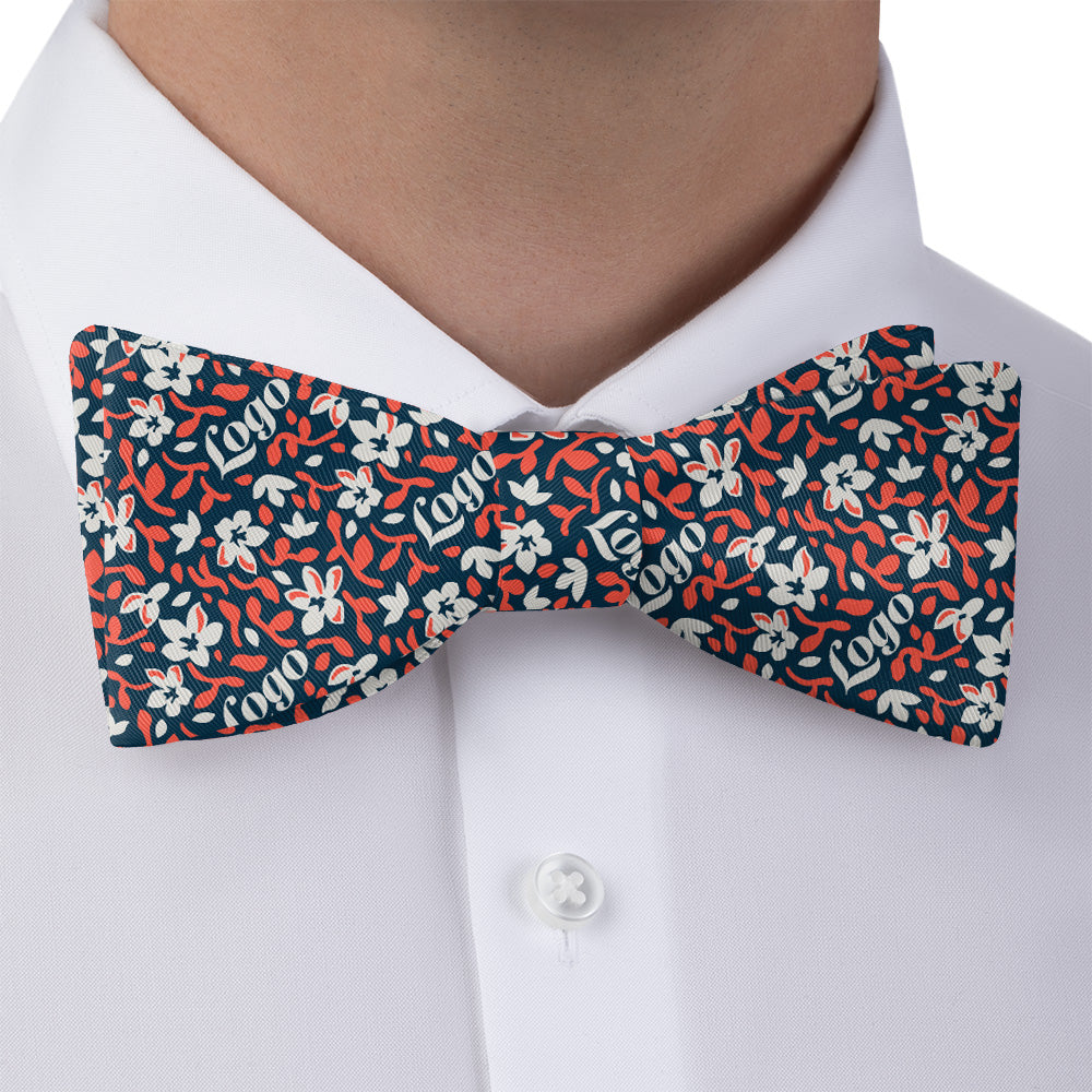 Floral patterned logo bow tie worn by a person on a white shirt