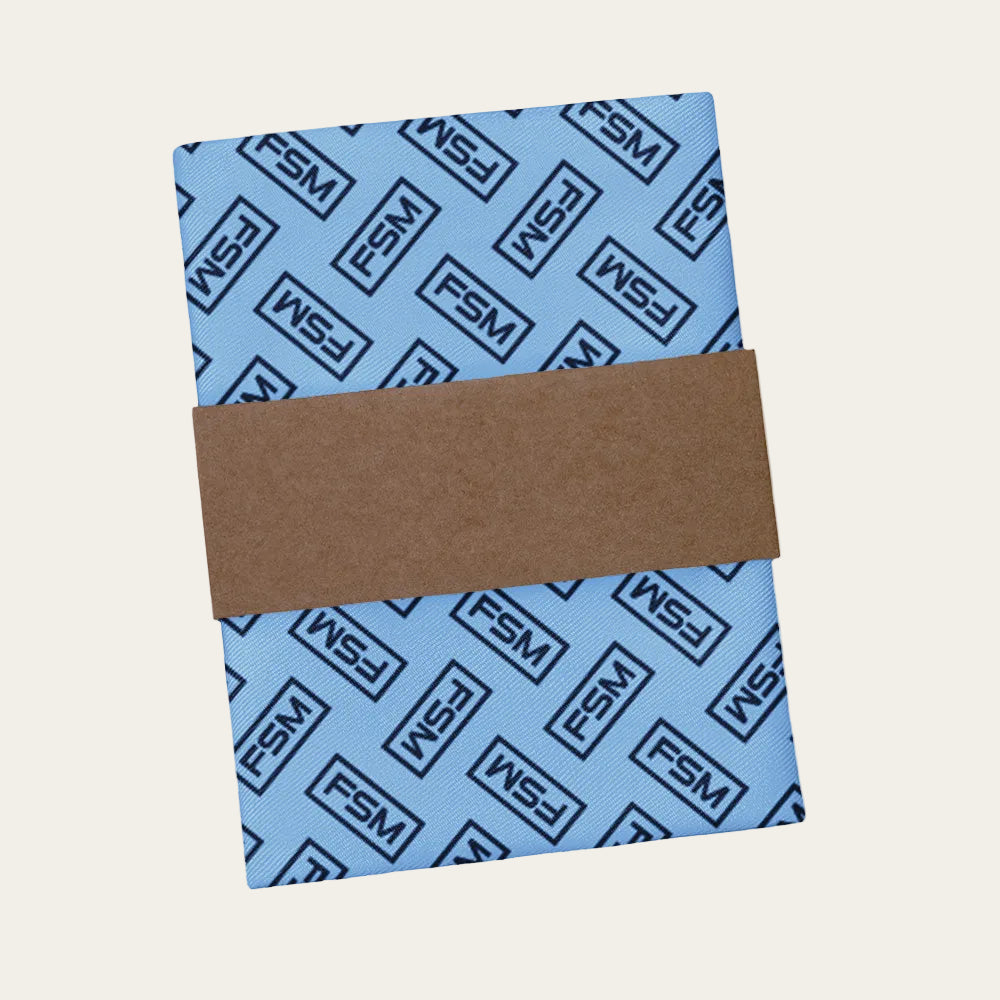 Blue pocket square with black 'FSM' logo and brown packaging band on a white background