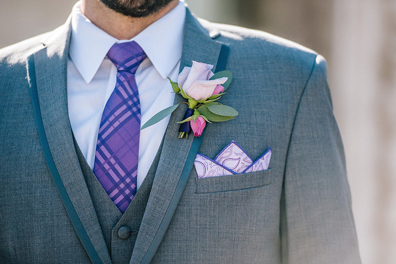 Gray suit with purple tie and pocket square on a blurred background
