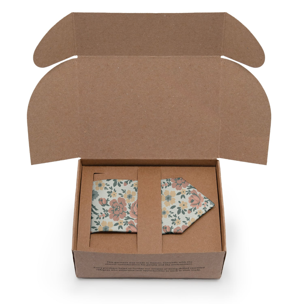 Open cardboard box with floral-patterned dress tie inside on a white background