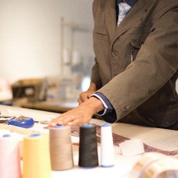 Person working with spools of thread on a table in a sewing setting.