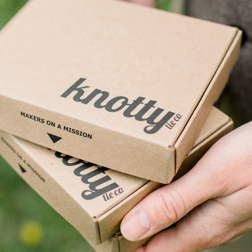 hands holding stacked tie boxes