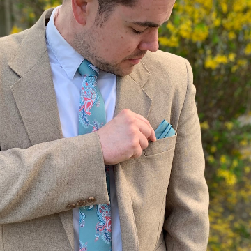 man wearing green paisley tie and solid  pocket square