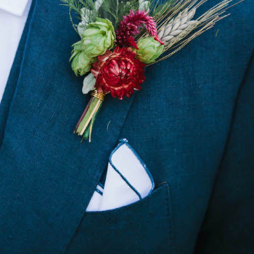 Navy blue suit with a floral boutonniere and white pocket square.