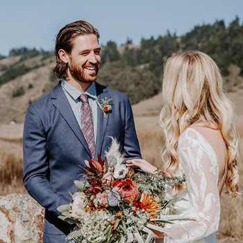 Man and woman holding hands with bouquets in a natural setting